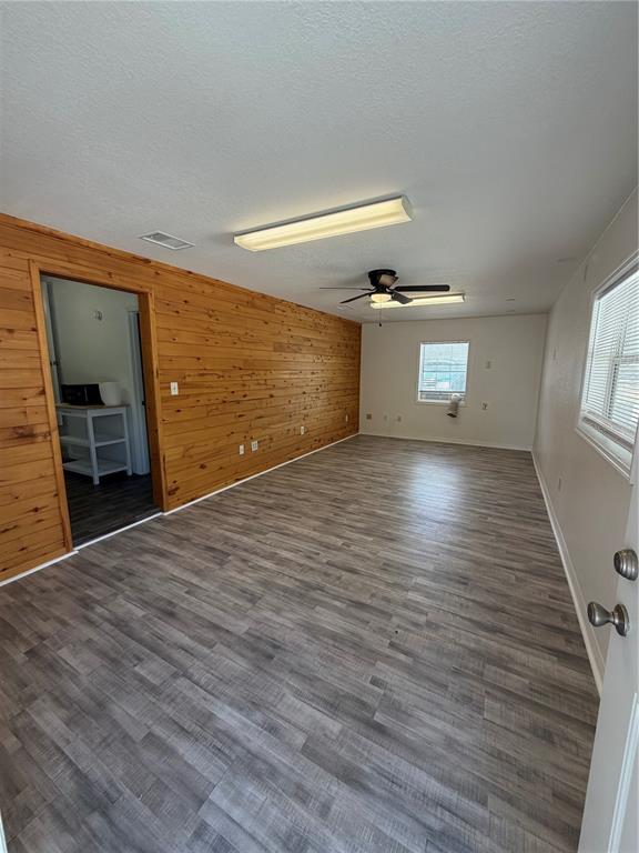 A room with wood-paneled walls, gray wood-look flooring, a ceiling fan, and a doorway — 306 N IONA AVENUE, FRUITLAND PARK, FL