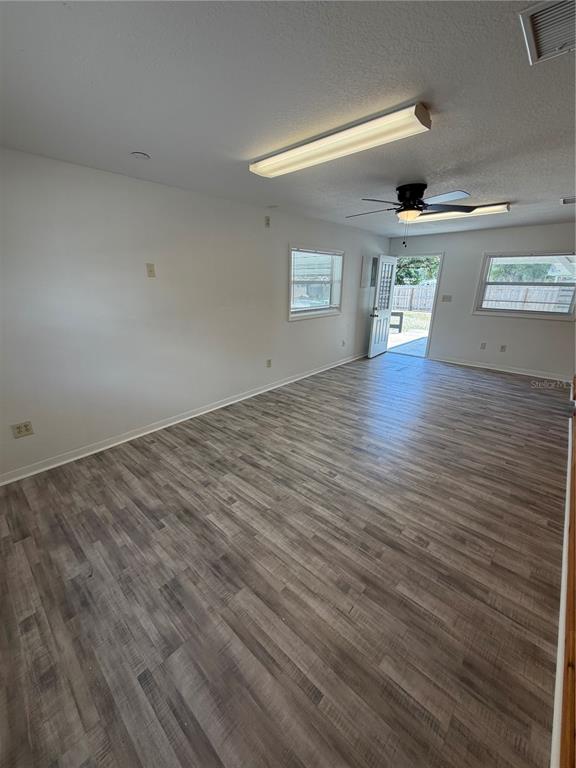 An empty room with light wood-look flooring, a ceiling fan, and a glass-paneled exterior door — 306 N IONA AVENUE, FRUITLAND PARK, FL