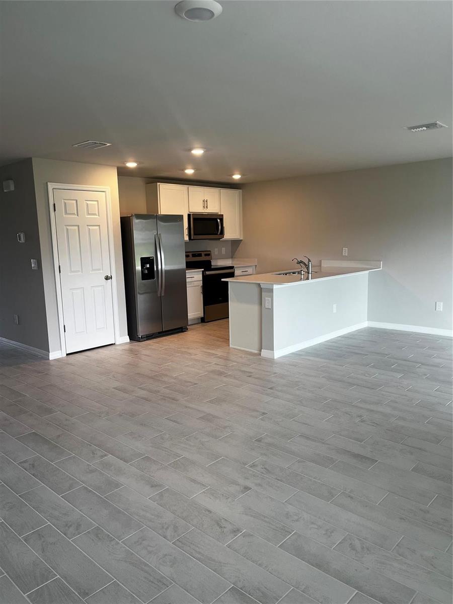 A kitchen with stainless steel appliances and a peninsula island sits in an open room — 4021 35th Street, Lehigh Acres FL 33976, LEHIGH ACRES, FL