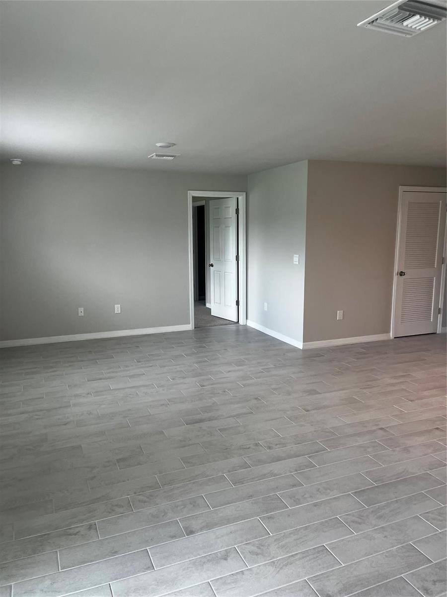 An empty room with gray walls, light wood-look tile flooring, and two white doors — 4021 35th Street, Lehigh Acres FL 33976, LEHIGH ACRES, FL