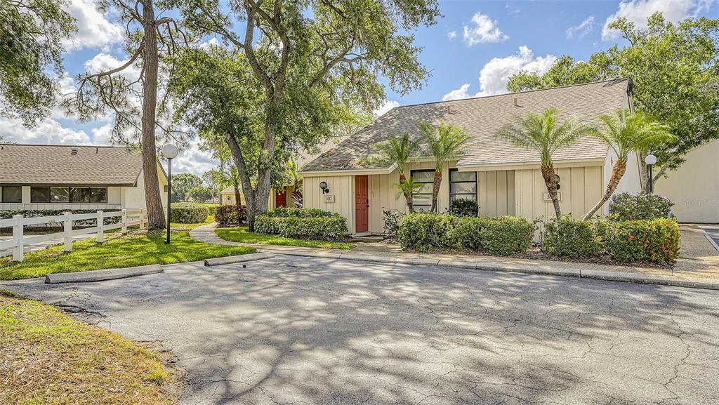 A one-story residential building with a red door, tan siding, and a paved parking area — 3127 LONGMEADOW UNIT 2, SARASOTA, FL