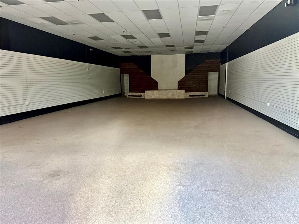 An empty commercial space features gray slat walls, a drop ceiling, and a raised platform — 2510 MICHIGAN AVENUE UNIT A, KISSIMMEE, FL