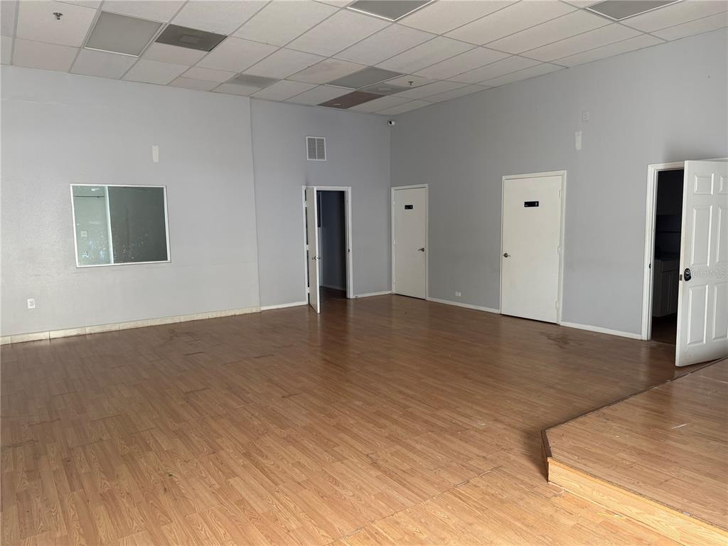 An empty commercial room with light wood-look flooring, gray walls, and a drop ceiling — 2510 MICHIGAN AVENUE UNIT A, KISSIMMEE, FL