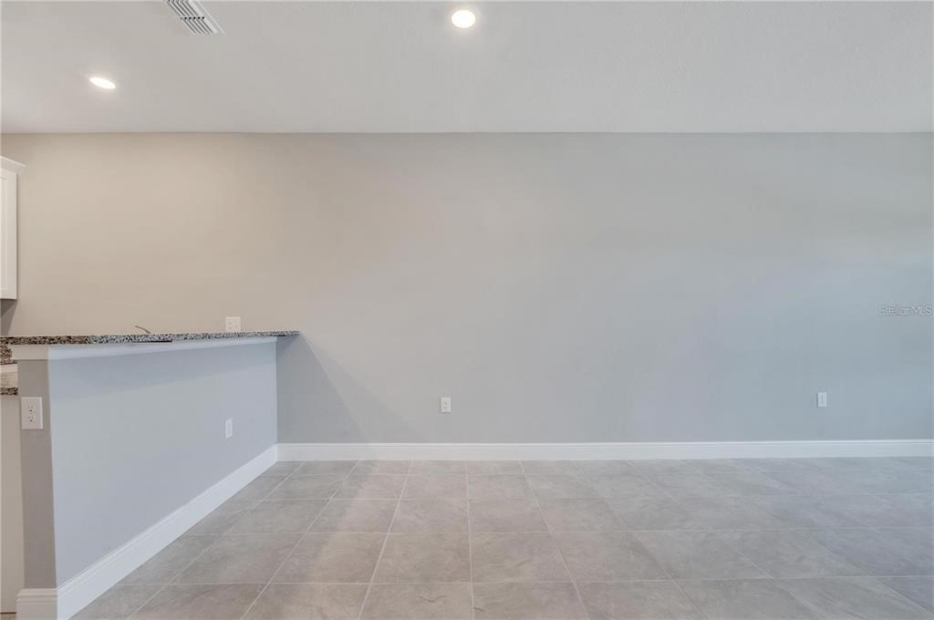A room with gray walls, tile flooring, and a granite-topped kitchen breakfast bar — 1746 CORIANDER DRIVE UNIT 1746, KISSIMMEE, FL