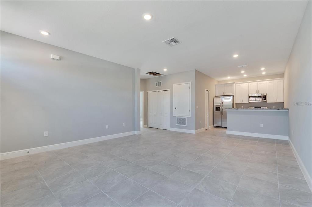 An open-concept living area with light gray tile flooring, white cabinets, and stainless steel appliances — 1746 CORIANDER DRIVE UNIT 1746, KISSIMMEE, FL