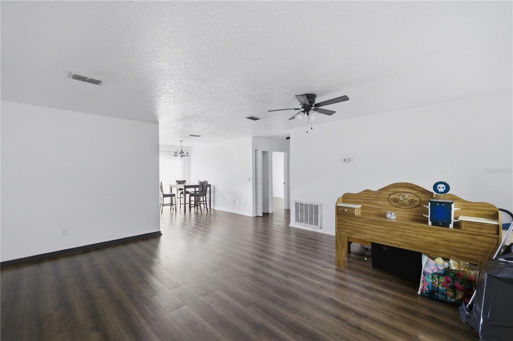 A living room with dark wood-look flooring, white walls, and a wooden headboard — 47 WATER TRACK LOOP, OCALA, FL