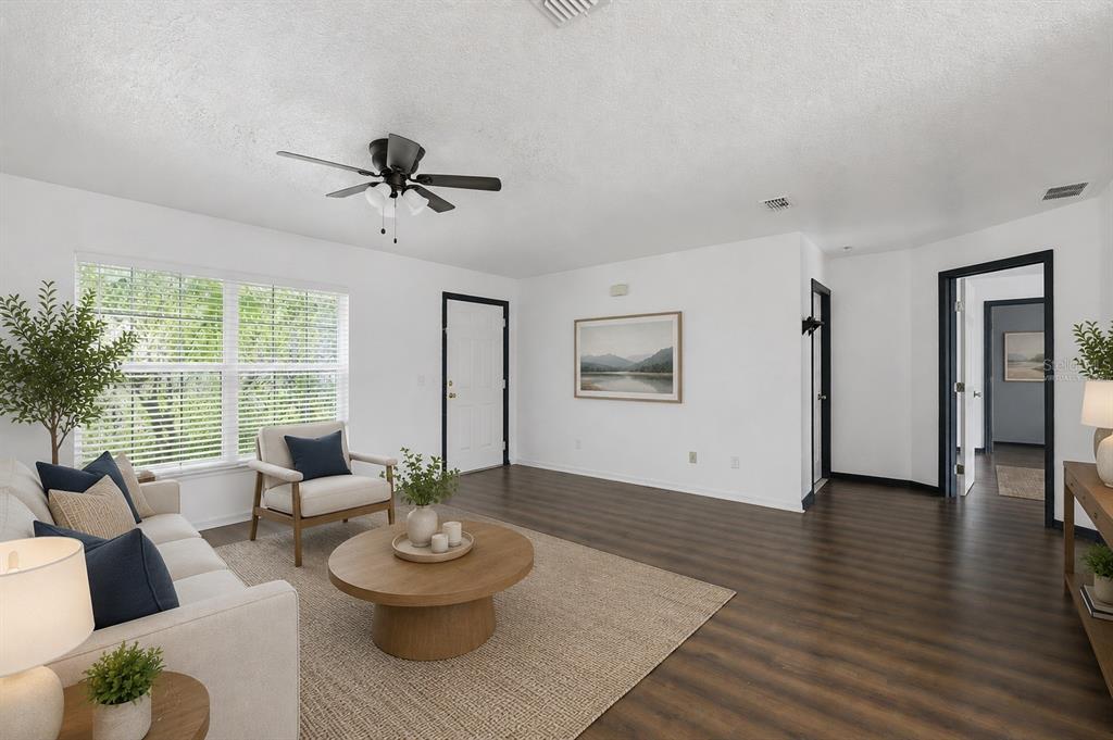 A living room with wood-look flooring, a ceiling fan, and a beige sofa — 47 WATER TRACK LOOP, OCALA, FL