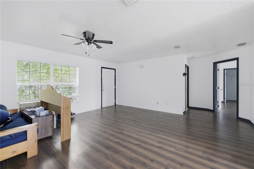 An empty room with white walls, dark wood-look flooring, a ceiling fan, and two doorways — 47 WATER TRACK LOOP, OCALA, FL