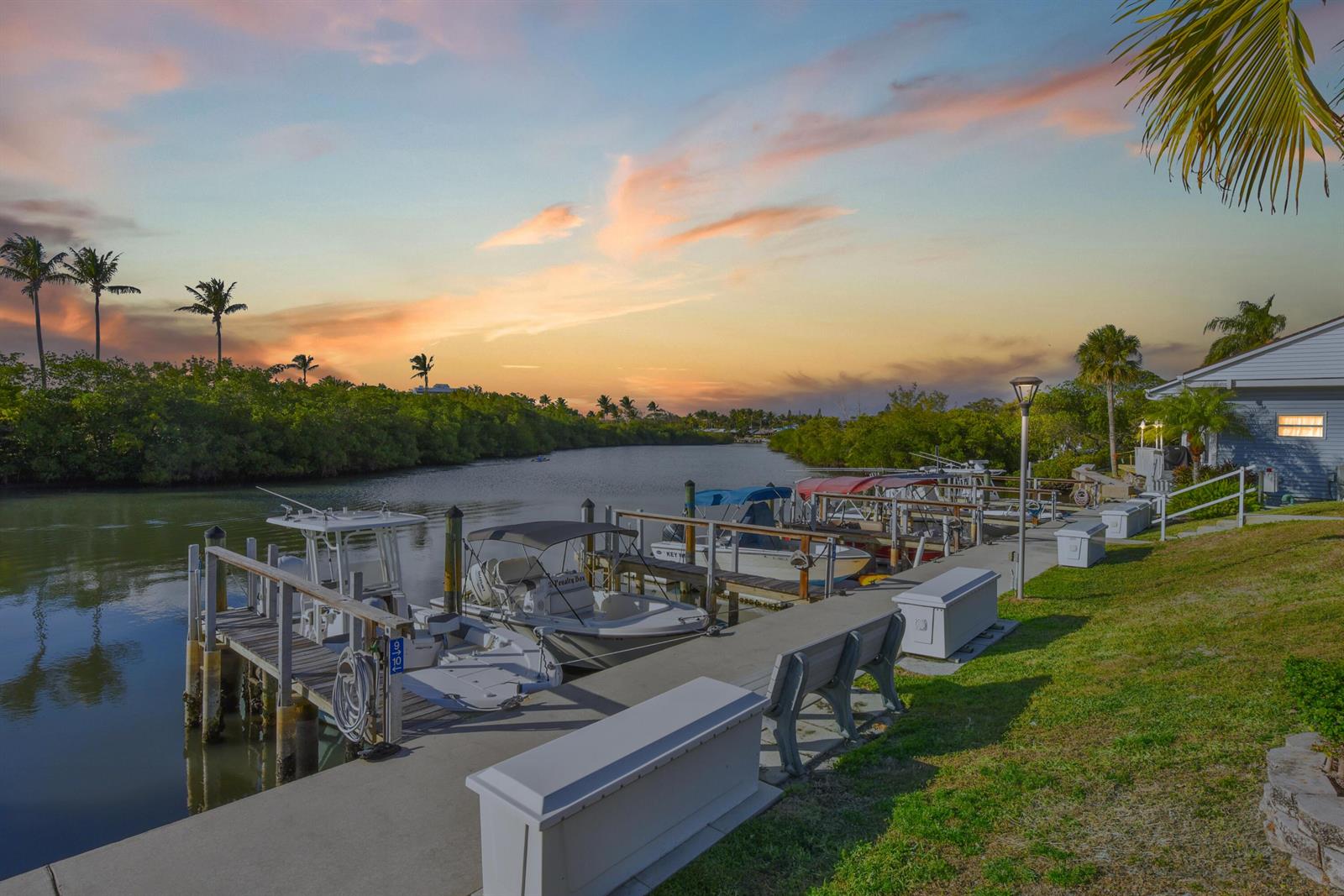 A concrete dock with several moored boats sits along a canal at sunset — 400 N N Highway A1a Highway Lot 64, Jupiter FL 33477, JUPITER, FL