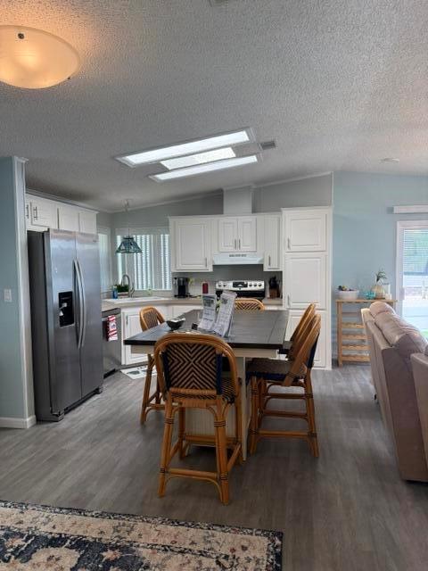 A kitchen features white cabinets, a dark island with wicker stools, and stainless steel appliances — 400 N N Highway A1a Highway Lot 64, Jupiter FL 33477, JUPITER, FL
