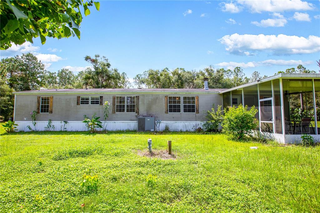 The exterior of a single-story manufactured home with a screened-in porch and a grassy yard — 104 EVERETT STREET, PALATKA, FL