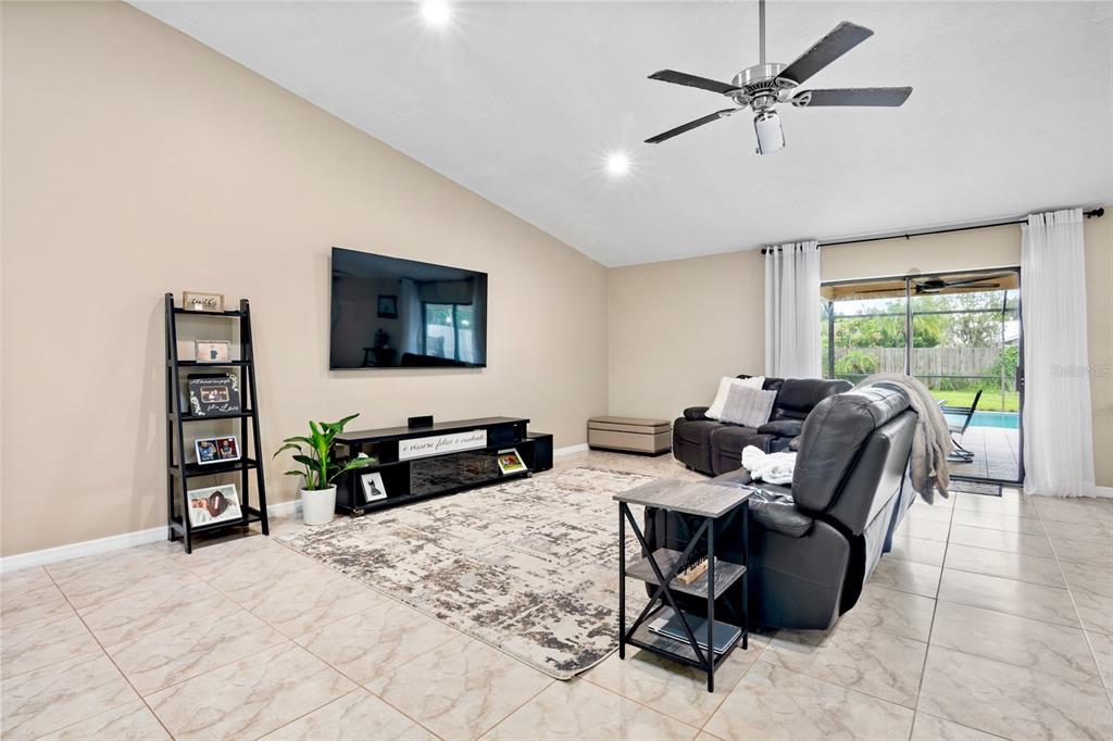 A living room features a wall-mounted television, a black media console, and a leather sofa — 6816 MAUNA LOA BOULEVARD, SARASOTA, FL