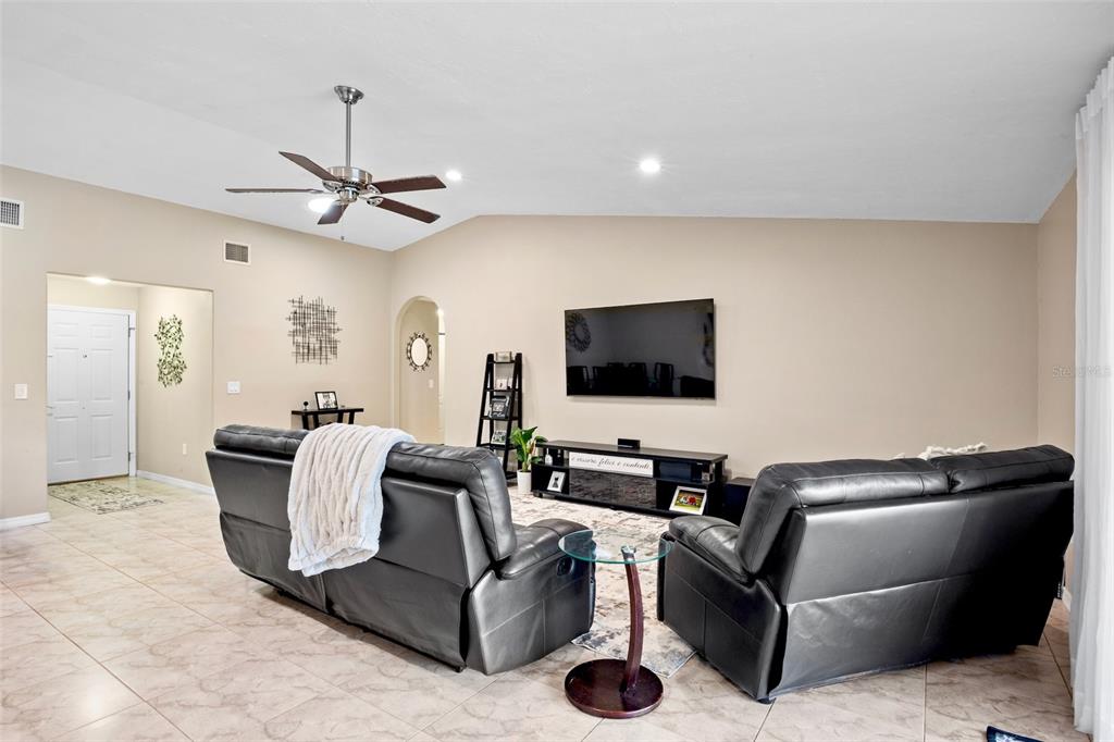 A living room features tile flooring, two black leather sofas, and a wall-mounted television — 6816 MAUNA LOA BOULEVARD, SARASOTA, FL