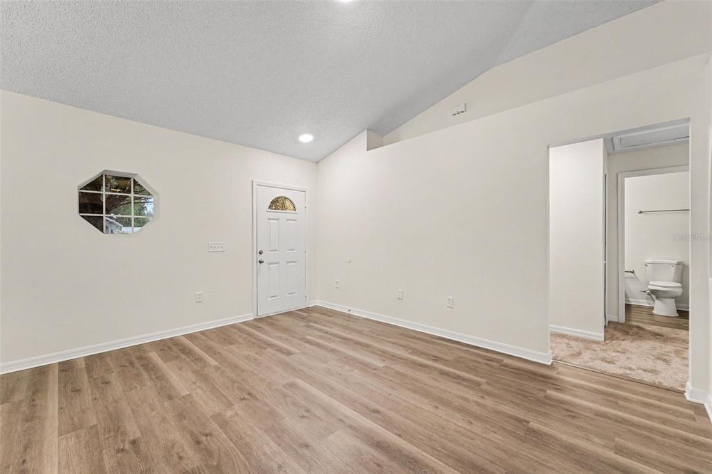 A room with light-colored walls, wood-look flooring, a vaulted ceiling, and an attached bathroom — 1228 WELCH RIDGE TERRACE, APOPKA, FL