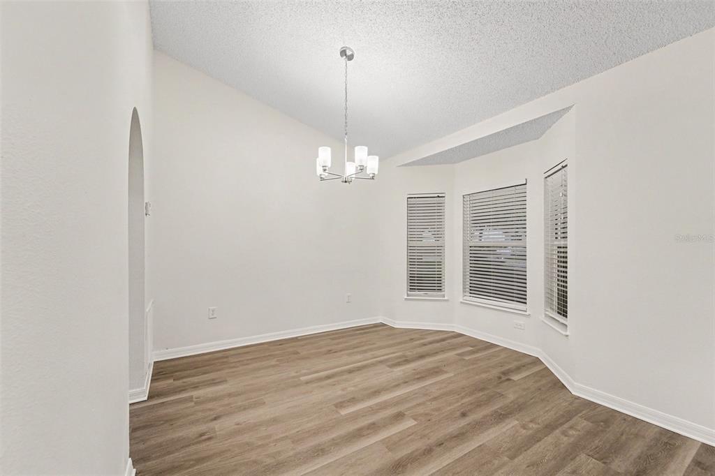 An empty dining room features light wood-look flooring, white walls, and a modern chandelier — 1228 WELCH RIDGE TERRACE, APOPKA, FL