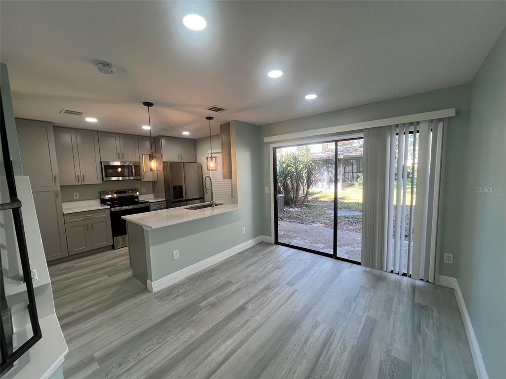 A kitchen with gray cabinets and a breakfast bar opens to a dining area — 2906 CANDELA COURT, APOPKA, FL