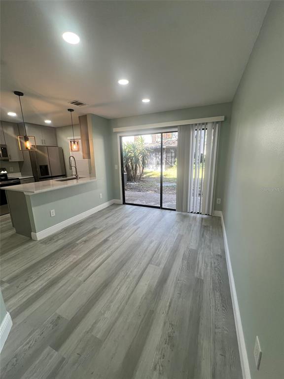 A dining area with wood-look flooring, recessed lighting, and a sliding glass door to outside — 2906 CANDELA COURT, APOPKA, FL