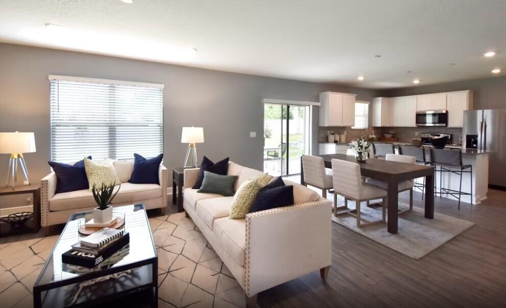 An open-concept living and dining area features neutral walls, light-colored sofas, and a modern kitchen — 1248 Caloosa Cove Drive, FL 33935, FL