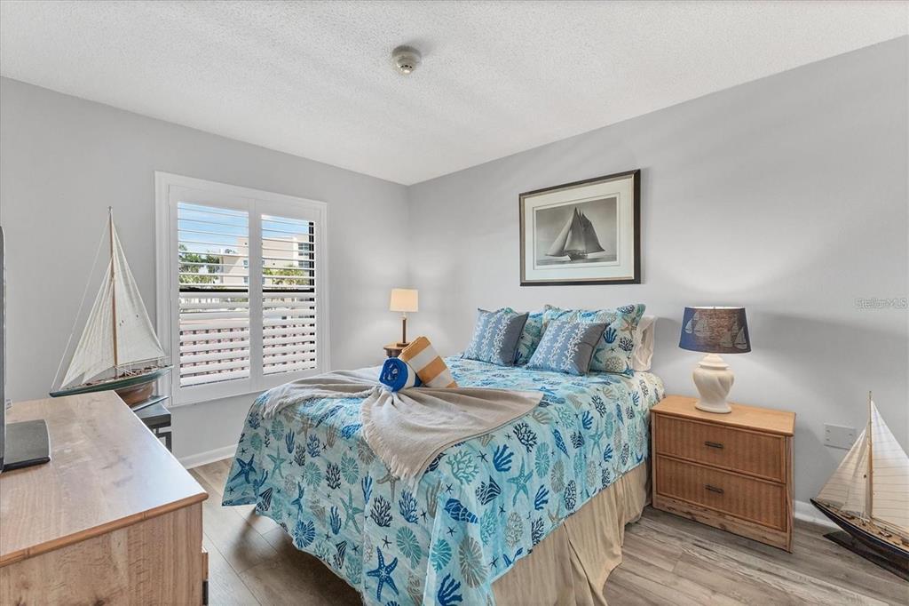 A bedroom features a bed with nautical-themed bedding, two model sailboats, and light wood flooring — 6480 MIDNIGHT PASS ROAD UNIT 311, SARASOTA, FL