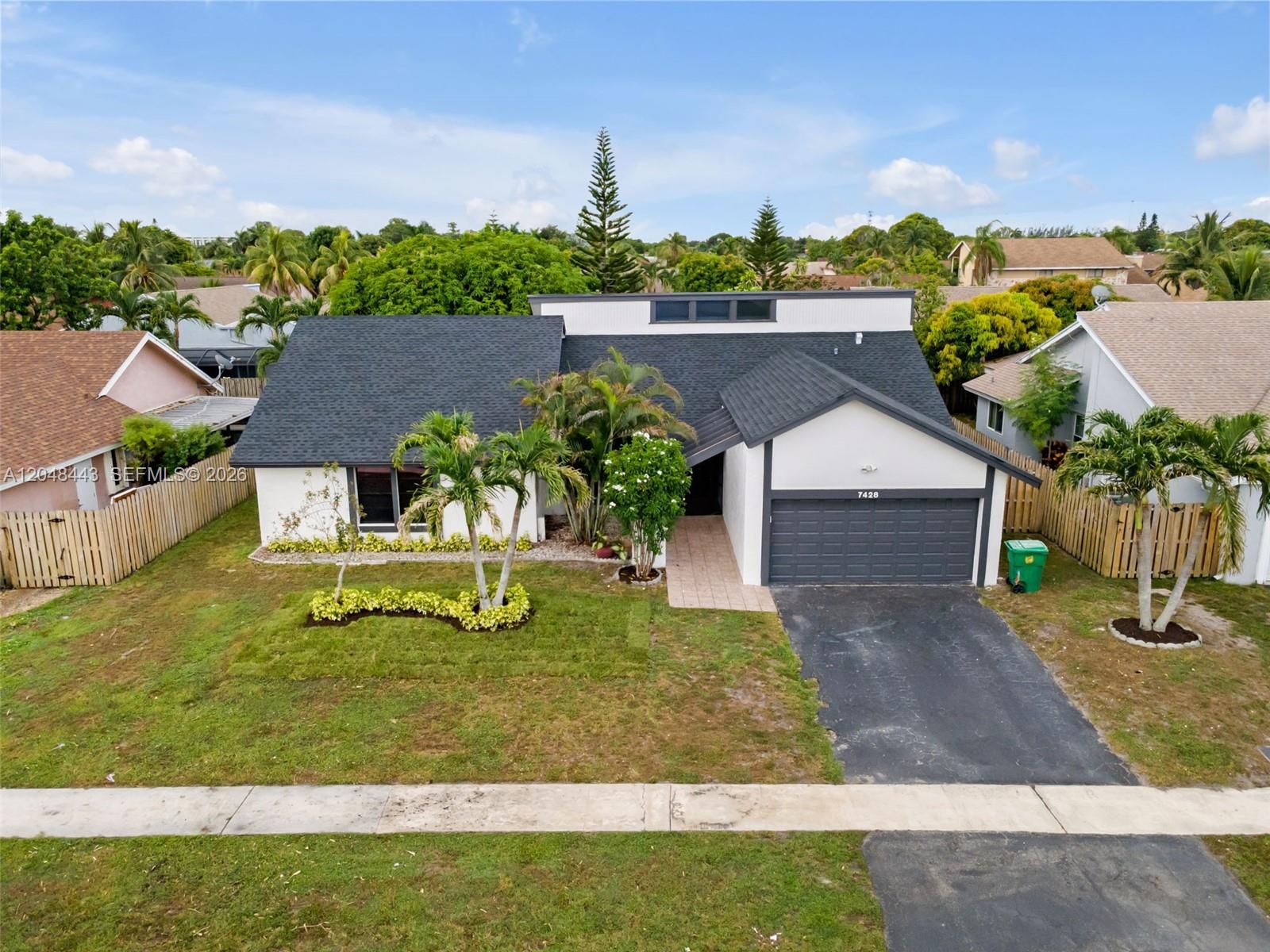 An aerial view of a single-story house with a dark roof, white walls, and driveway — 7428 NW 49th Ct, Lauderhill FL 33319, LAUDERHILL, FL