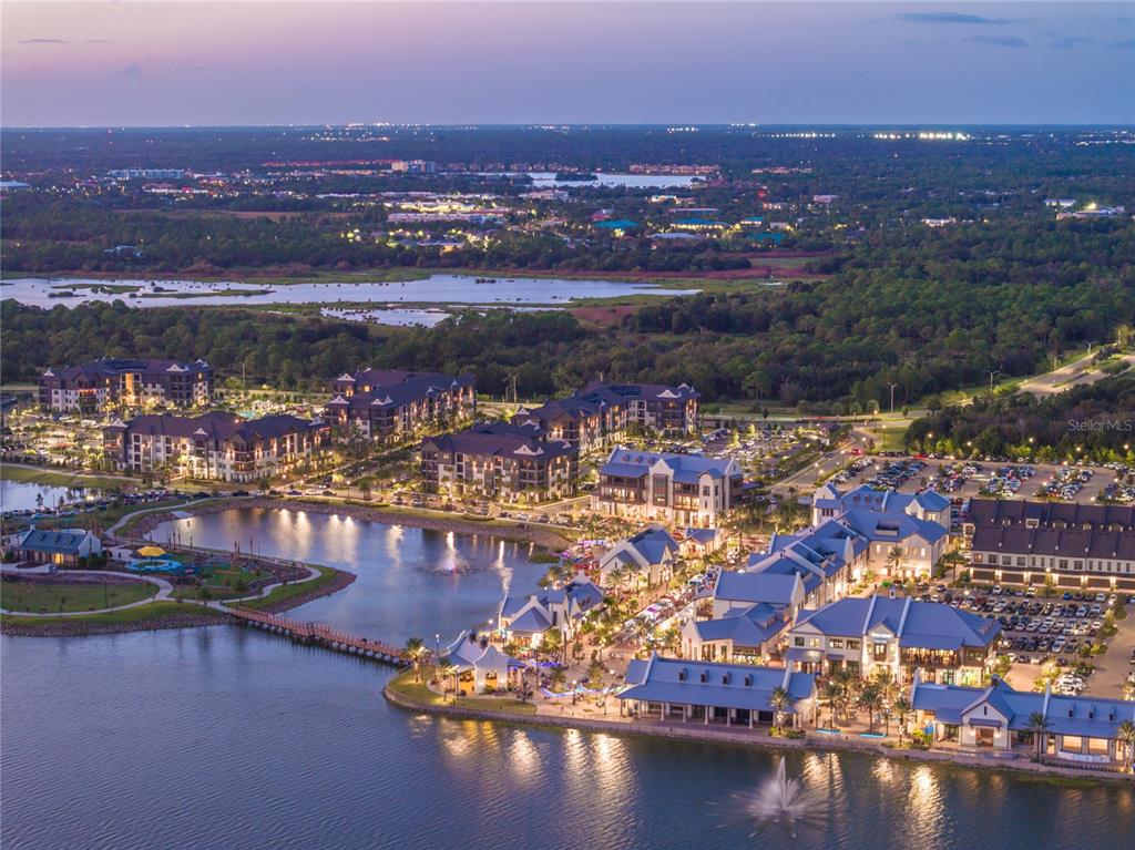 An aerial view shows a lakeside commercial and residential complex at dusk — 9085 CORMACK LANE, LAKEWOOD RANCH, FL