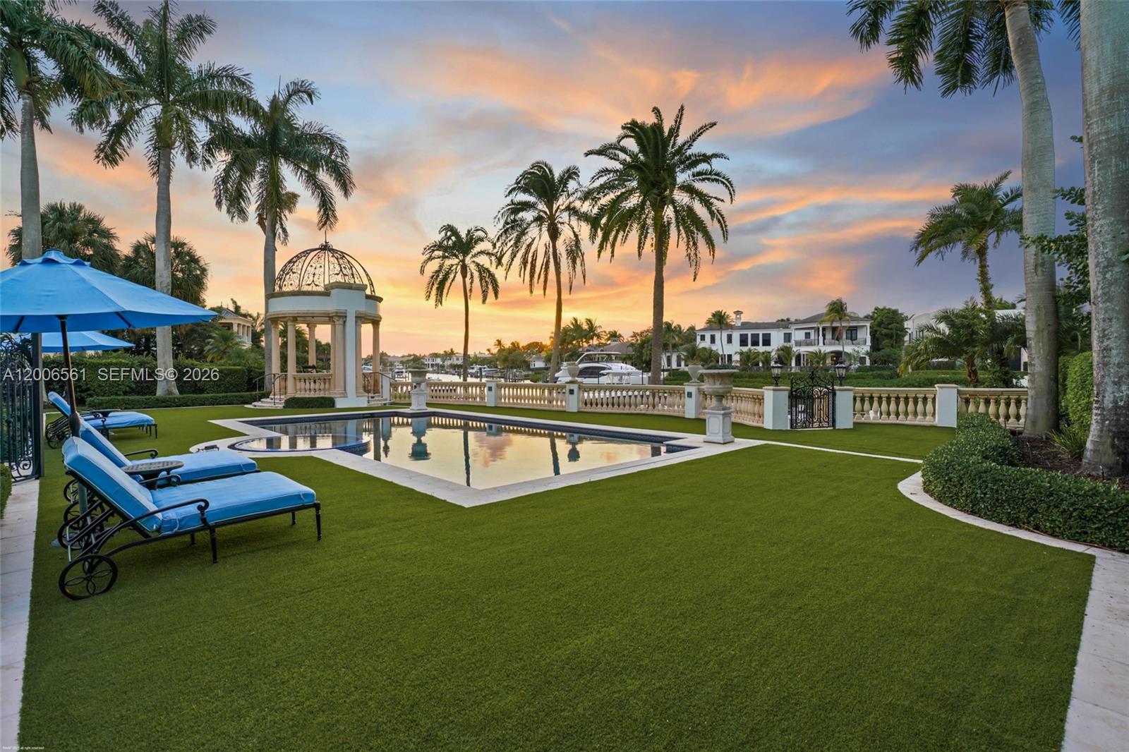 A swimming pool with lounge chairs and a gazebo sits on a lawn at sunset — 370 Eagle Dr, Jupiter FL 33477, JUPITER, FL