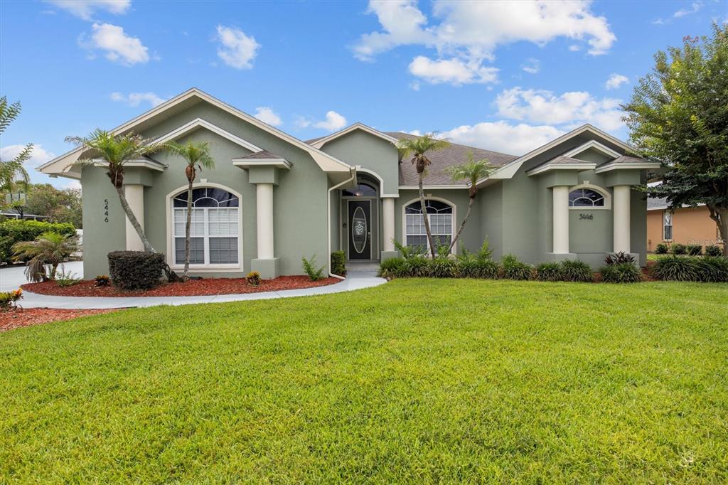 A single-story green house with a front lawn, arched windows, and a covered entryway — 5446 HIGHLANDS VISTA CIRCLE, LAKELAND, FL