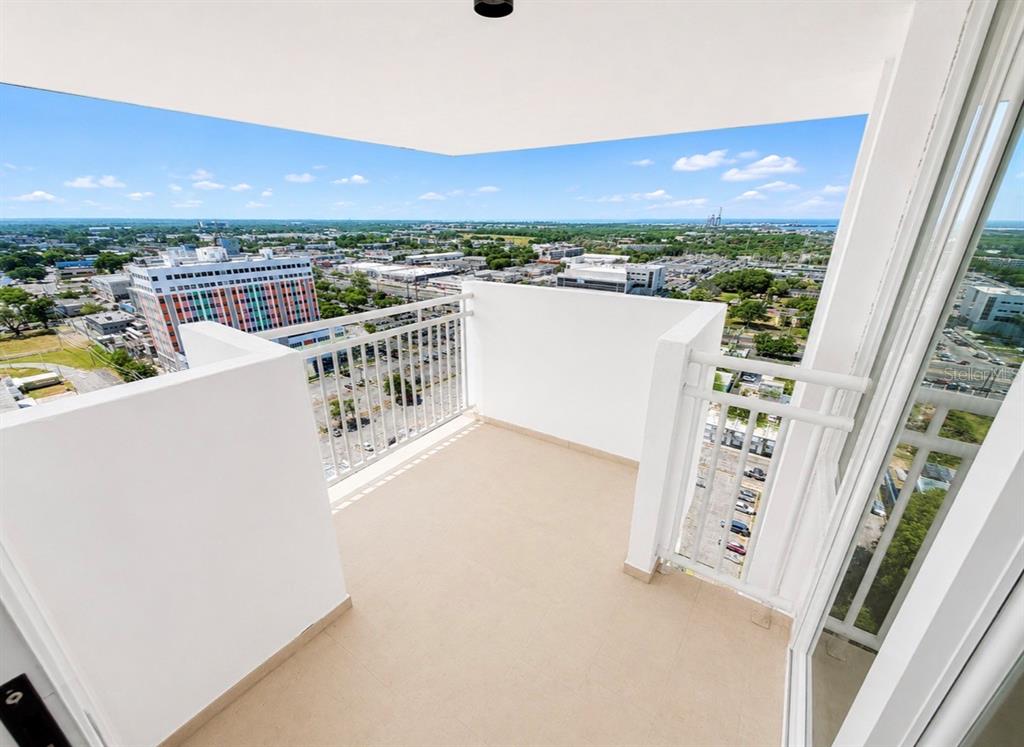 A high-rise balcony features white railings, tiled flooring, and an expansive urban city view — 2325 UNIVERDIDAD STREET UNIT 2302, PONCE, PR