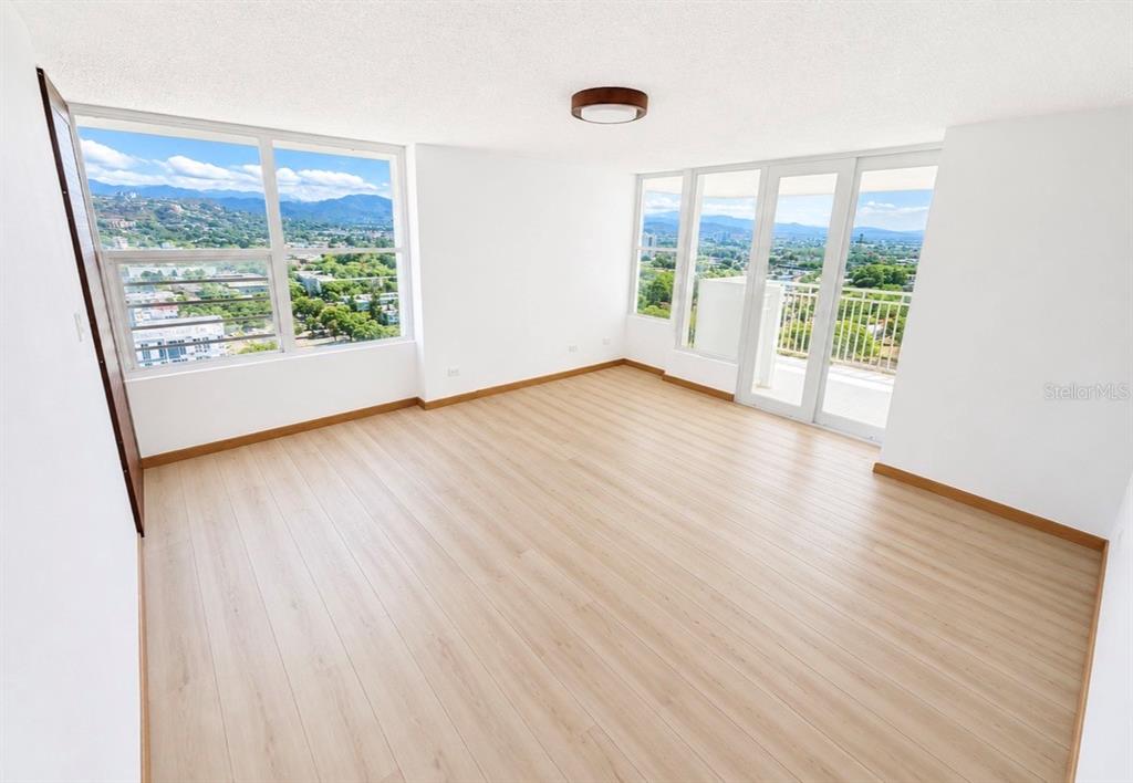 An empty room with light wood flooring, white walls, large windows, and a balcony door — 2325 UNIVERDIDAD STREET UNIT 2302, PONCE, PR
