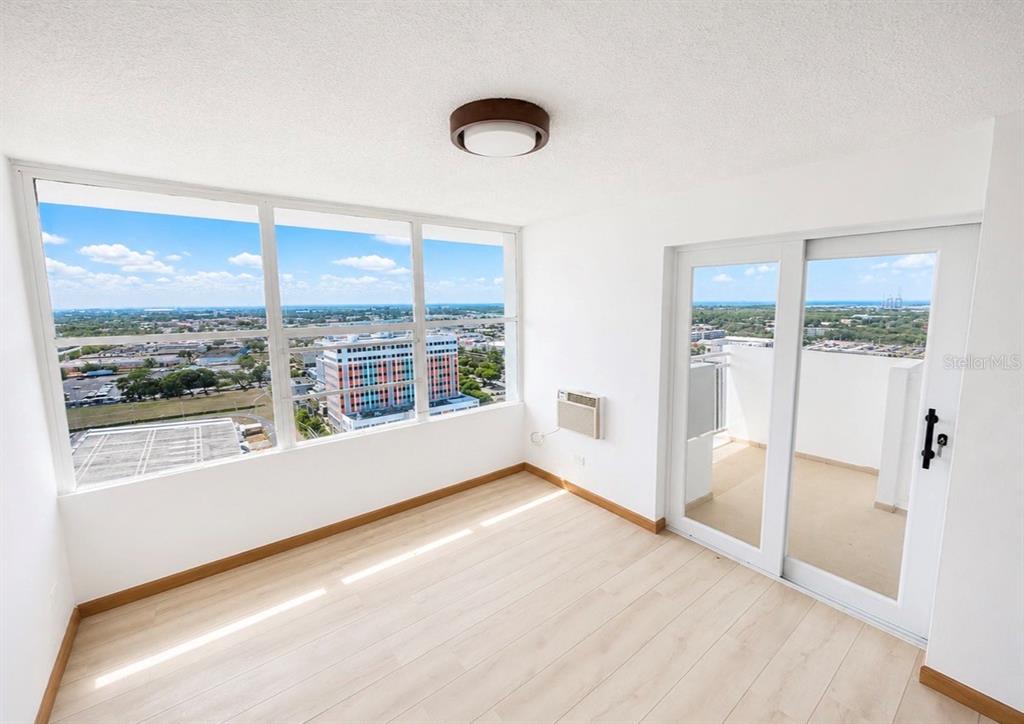 A bright room with light wood floors, large windows, and a sliding door to a balcony — 2325 UNIVERDIDAD STREET UNIT 2302, PONCE, PR