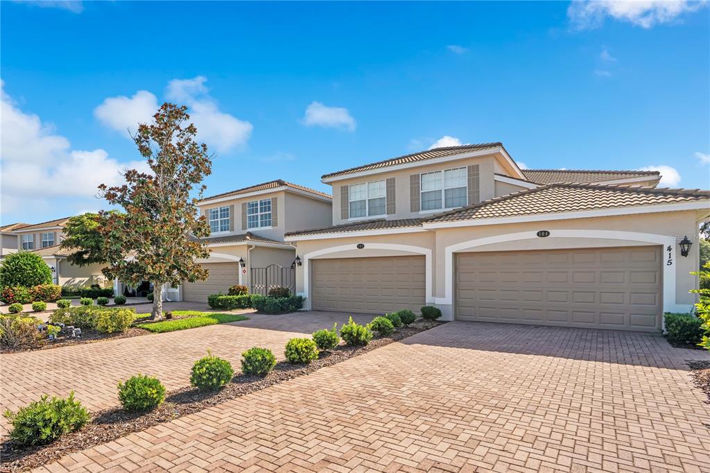 A two-story residential building with a brick paver driveway and three garage doors — 415 WINDING BROOK LANE UNIT 102, BRADENTON, FL