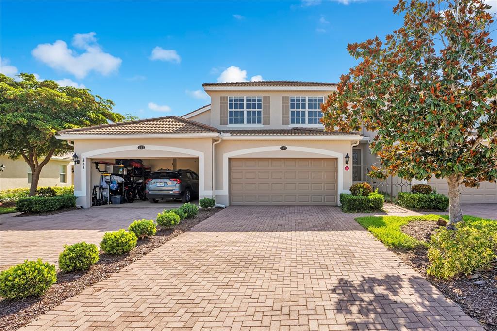 A two-story house with a paved driveway, a one-car carport, and a one-car garage — 415 WINDING BROOK LANE UNIT 102, BRADENTON, FL