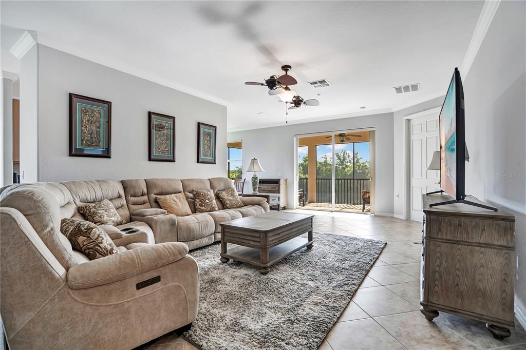 A living room features a beige sectional sofa, a wooden coffee table, and a balcony view — 415 WINDING BROOK LANE UNIT 102, BRADENTON, FL