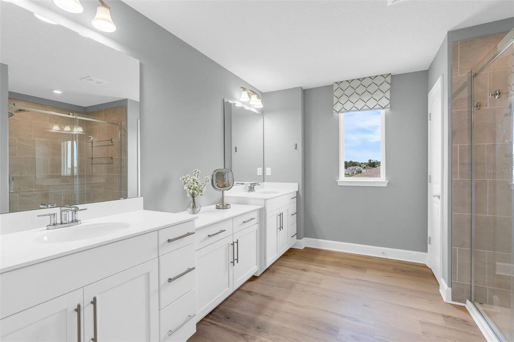 A bathroom features a double vanity with white cabinets, gray walls, and a glass shower — 3009 ROBLES ROAD, CLERMONT, FL