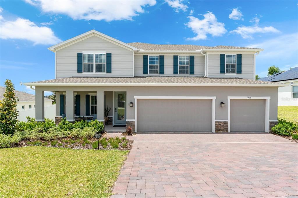 A two-story suburban house features light gray siding, blue shutters, and a three-car garage — 3009 ROBLES ROAD, CLERMONT, FL