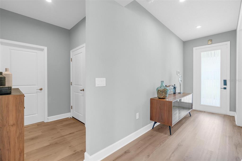 An entryway features light gray walls, wood-look flooring, two white doors, and a wooden console table — 3009 ROBLES ROAD, CLERMONT, FL