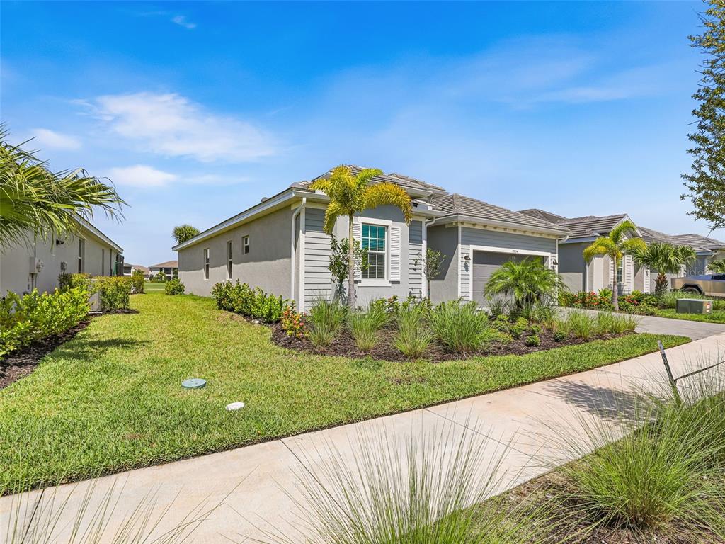 A single-story house with a gray stucco exterior, a two-car garage, and landscaped front yard — 15904 SUGAR HILL DRIVE, PUNTA GORDA, FL