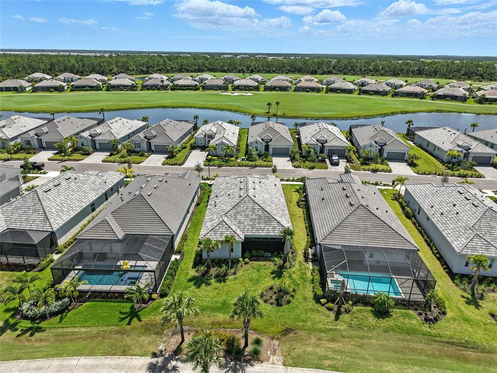 An aerial view shows several suburban houses with swimming pools and a golf course beyond — 15904 SUGAR HILL DRIVE, PUNTA GORDA, FL