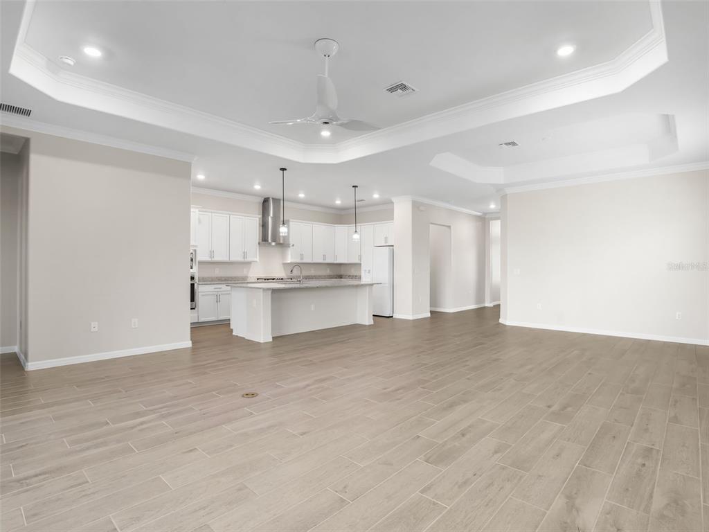 An open-concept kitchen with white cabinetry and a central island overlooks a large living area — 15904 SUGAR HILL DRIVE, PUNTA GORDA, FL