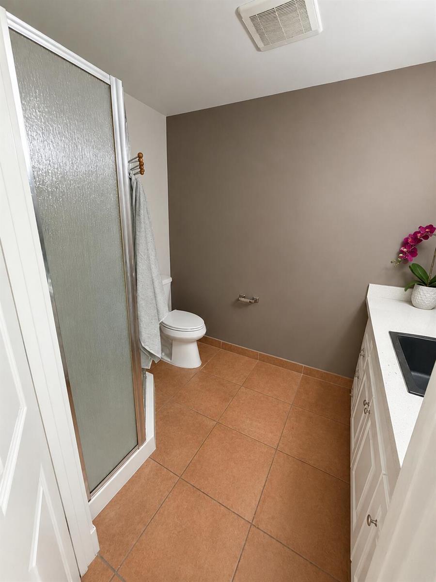A bathroom features a walk-in shower, a toilet, and a vanity with a white countertop — 2646 SE Willoughby Boulevard, Stuart FL 34994, STUART, FL