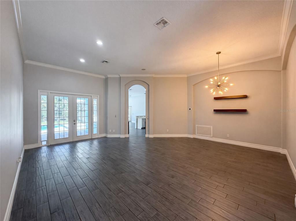 An empty room with dark wood-look tile flooring, a modern chandelier, and glass patio doors — 3100 CONRAD COURT, KISSIMMEE, FL