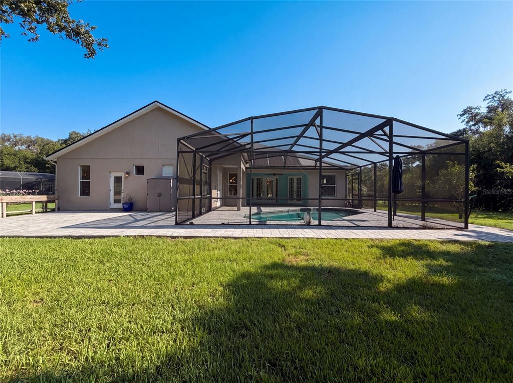 A house with a screened-in pool and a paved patio sits on a grassy lawn — 3100 CONRAD COURT, KISSIMMEE, FL