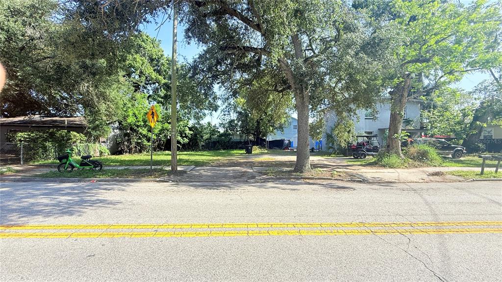 A vacant, tree-covered lot sits between two houses along a paved road — 824 W ROBINSON STREET, ORLANDO, FL