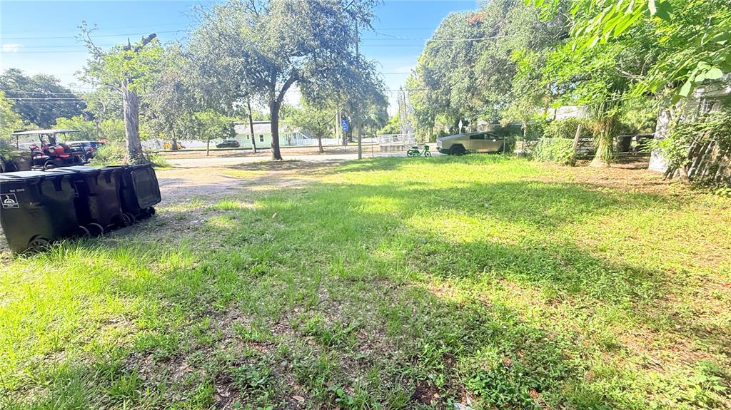A grassy, partially shaded vacant lot features several large trees and a few parked vehicles — 824 W ROBINSON STREET, ORLANDO, FL