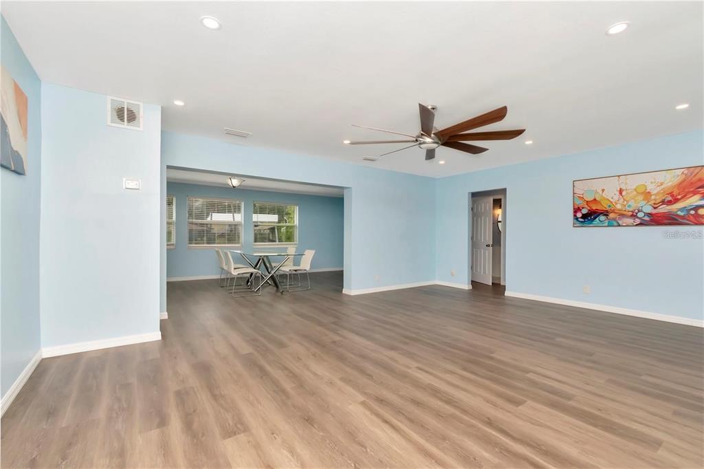 A spacious living area with light blue walls, wood-look flooring, and a dining nook — 4512 26TH AVENUE S, TAMPA, FL