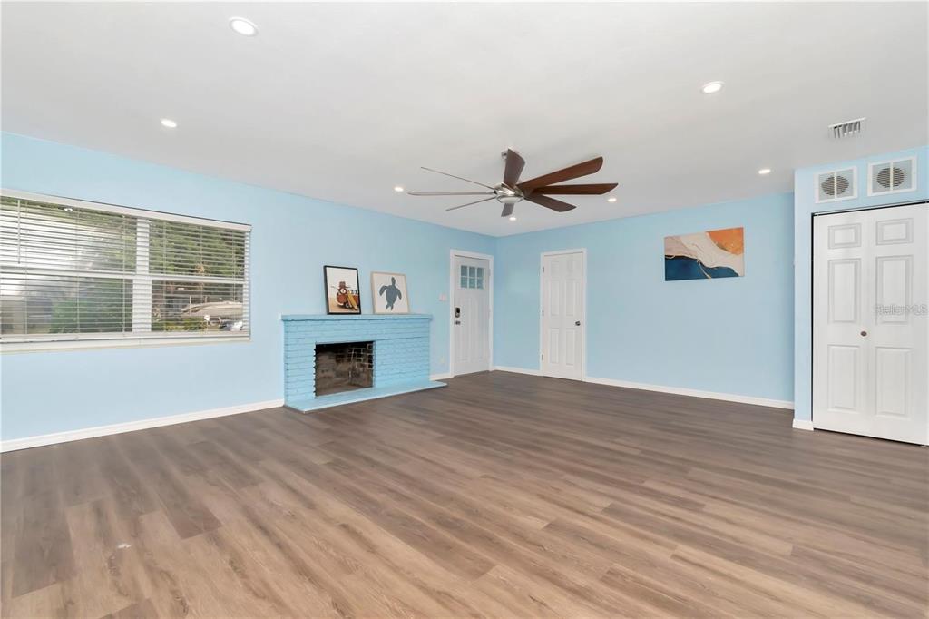 A living room with light blue walls, wood-look flooring, a brick fireplace, and a ceiling fan — 4512 26TH AVENUE S, TAMPA, FL