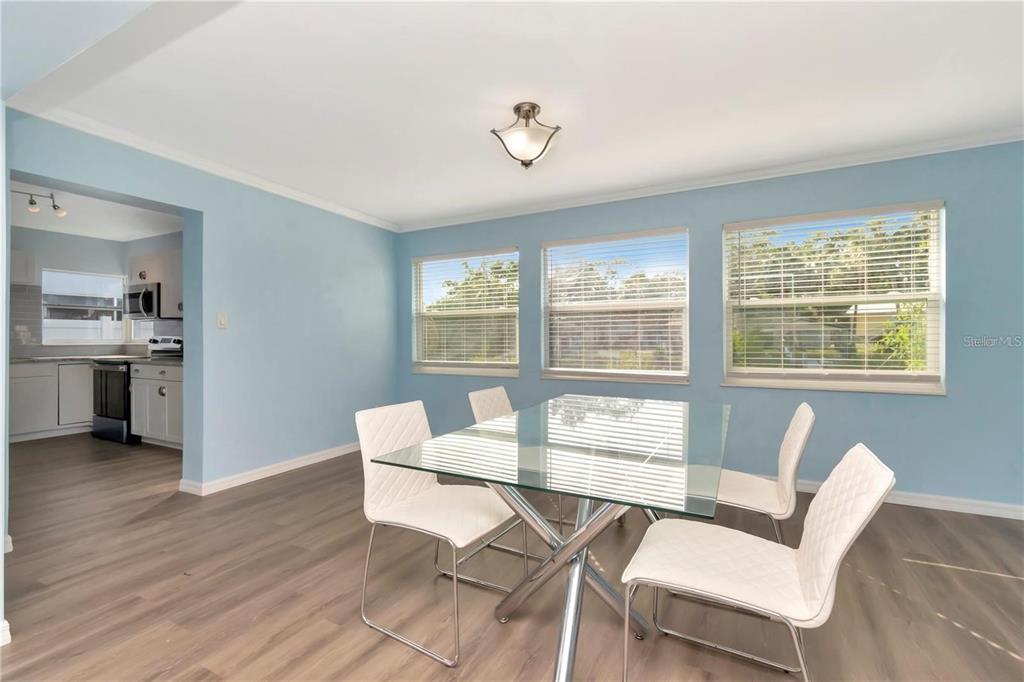 A dining room with light blue walls, wood-look flooring, and a glass-top table — 4512 26TH AVENUE S, TAMPA, FL
