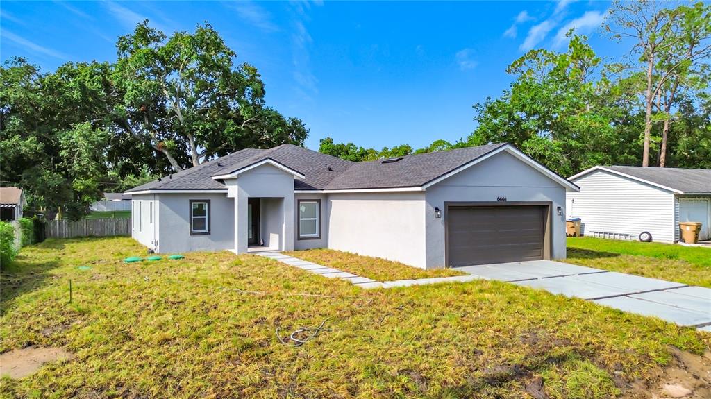 A single-story house with a gray stucco exterior, a dark roof, and a two-car garage — 6446 FALL STREET, ST CLOUD, FL