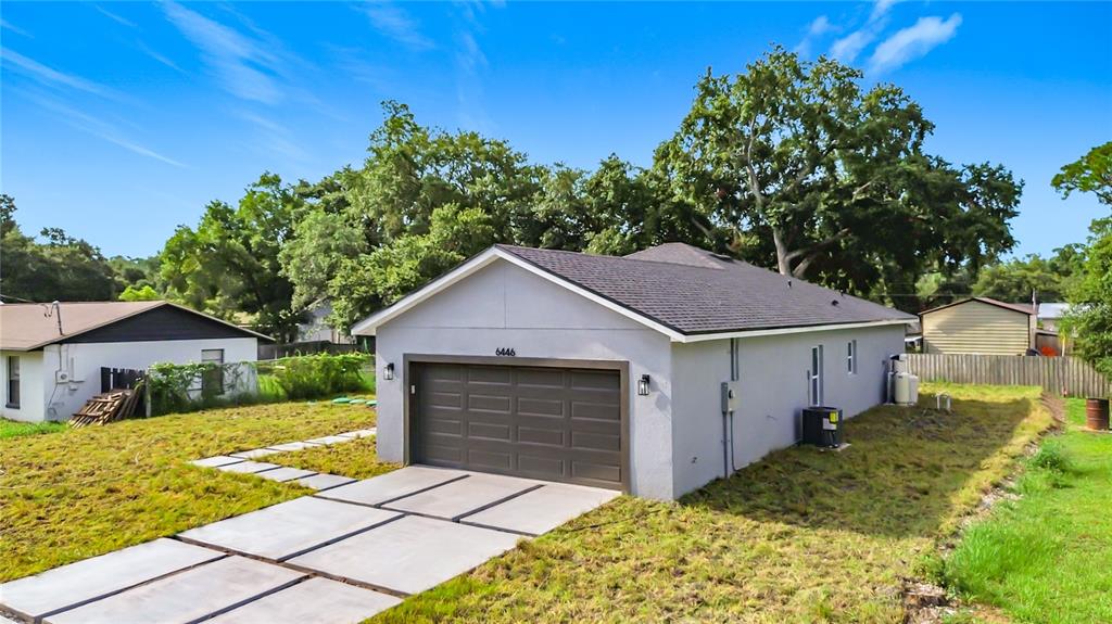 A gray detached garage with a brown door sits on a grassy lot with pavers — 6446 FALL STREET, ST CLOUD, FL