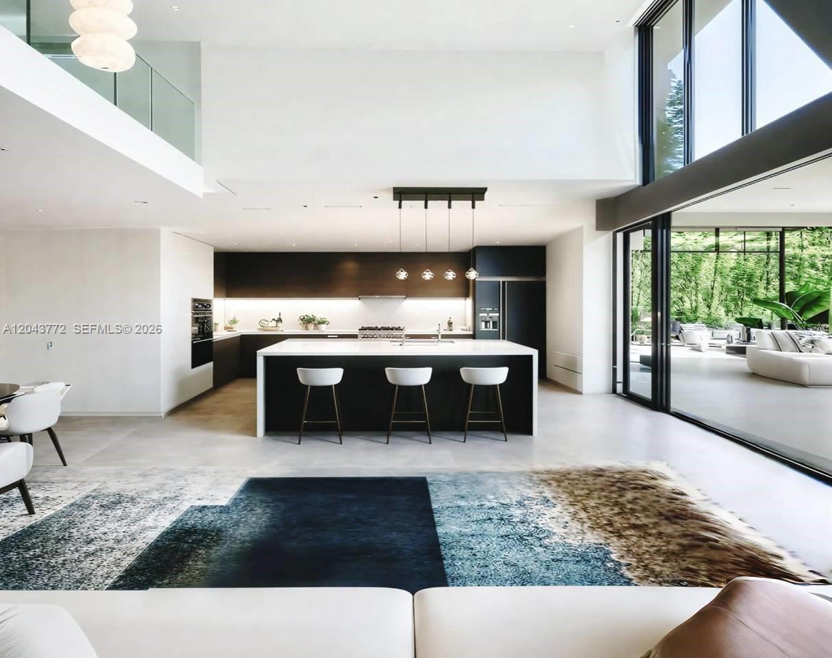 A modern open-concept kitchen features a large island, dark cabinetry, and floor-to-ceiling glass walls — 0 villa banyu, FL